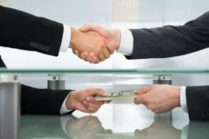 40579582 - close-up of businessman with money handshaking with his business partner