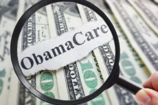 61314122 - obamacare newspaper headline on cash with magnifying glass