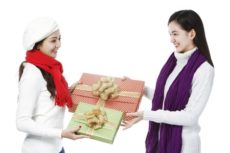 15595310 - two young women exchanging gifts on white background