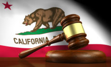 50994353 - california law, legal system and justice concept with a 3d render of a gavel on a wooden desktop and the californian flag on background.