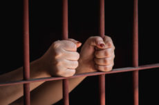 55354362 - hands of muslim woman holding bars in jail