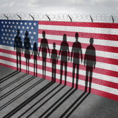 49949787 - american immigration and united states refugee crisis concept as people on a border wall with a us flag as a social issue about refugees or illegal immigrants with the cast shadow of a group of migrating women men and children.