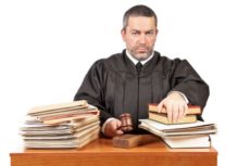 6527083 - angry male judge in a courtroom striking the gavel and pronounces sentence