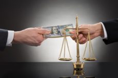 40579635 - close-up of a bureaucrat handing money to a political activist in front of justice scale